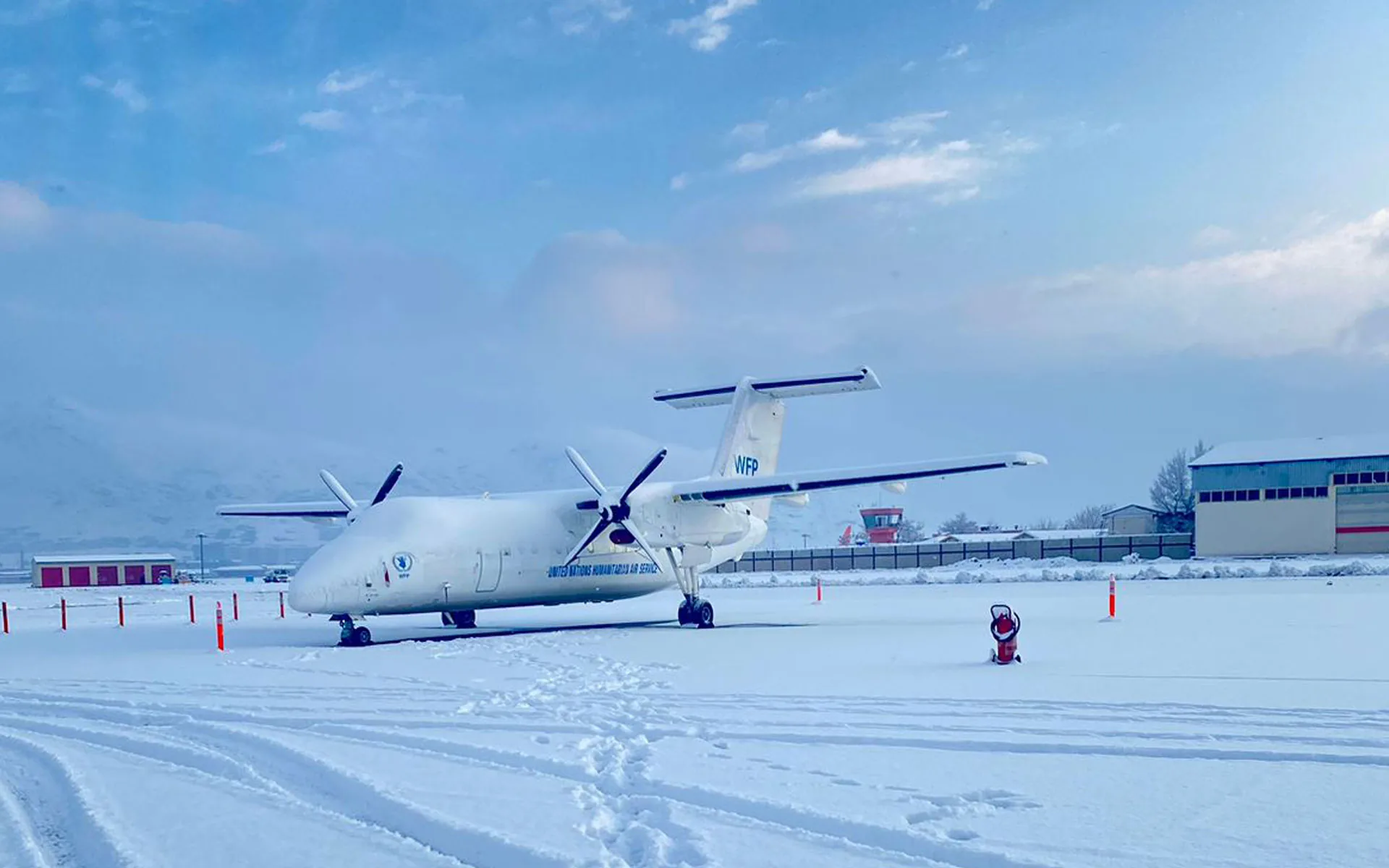 An ALS Dash 8-100 in UNHAS titles on a snow-covered apron