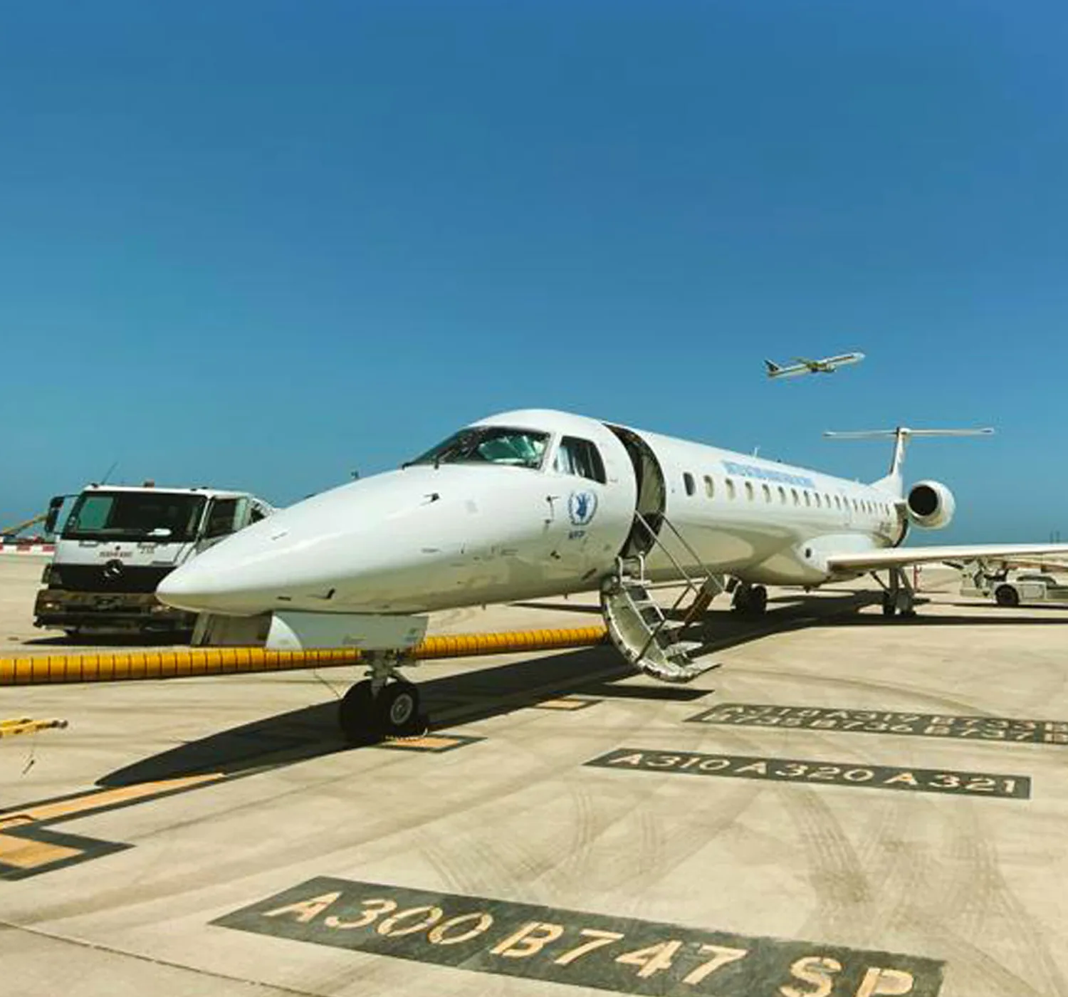 An ALS Embraer ERJ-145 in World Food Programme titles, airstair down, on a desert apron