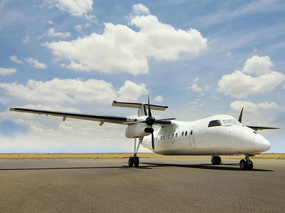 ALS Dash 8-100 in plain white on a wide apron under a cloud-dotted sky