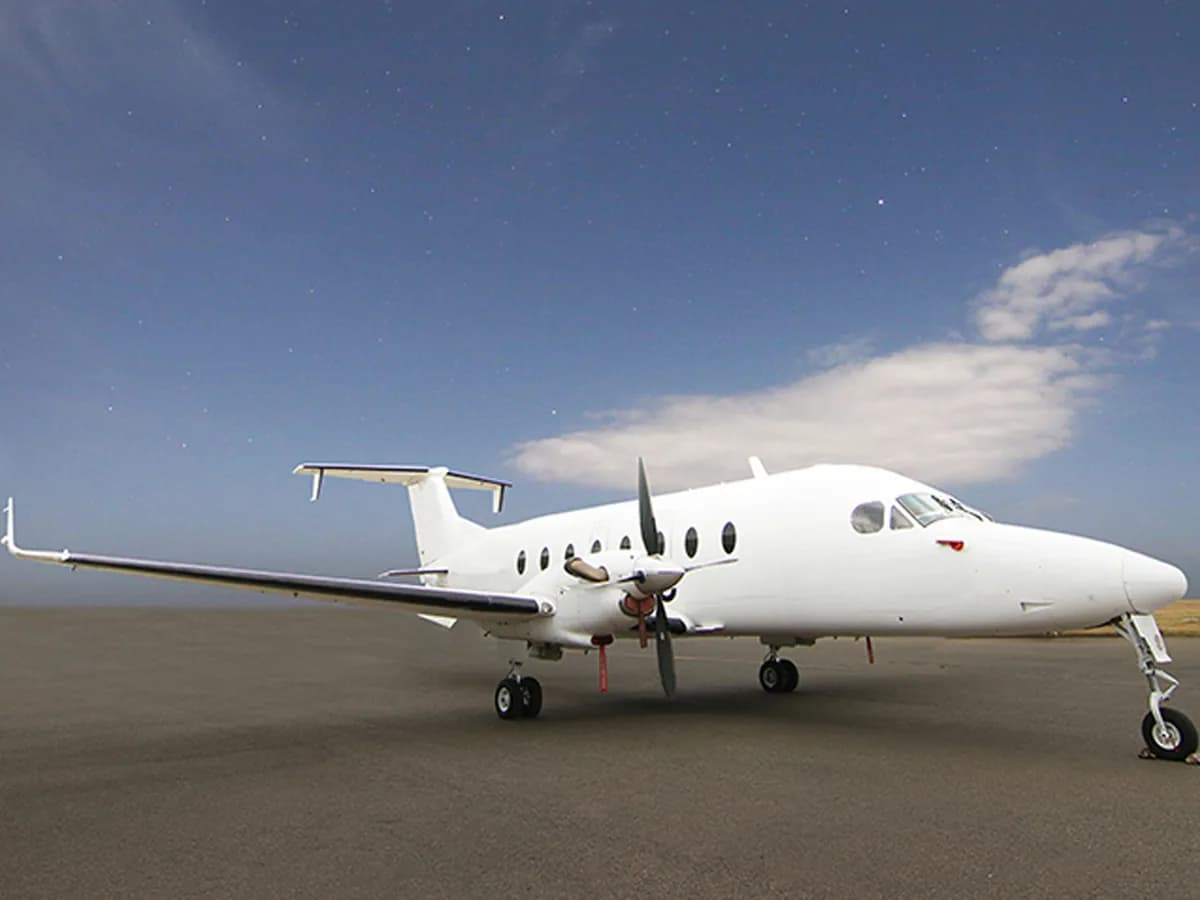 ALS Beechcraft 1900D in plain white on a wide apron under an evening sky